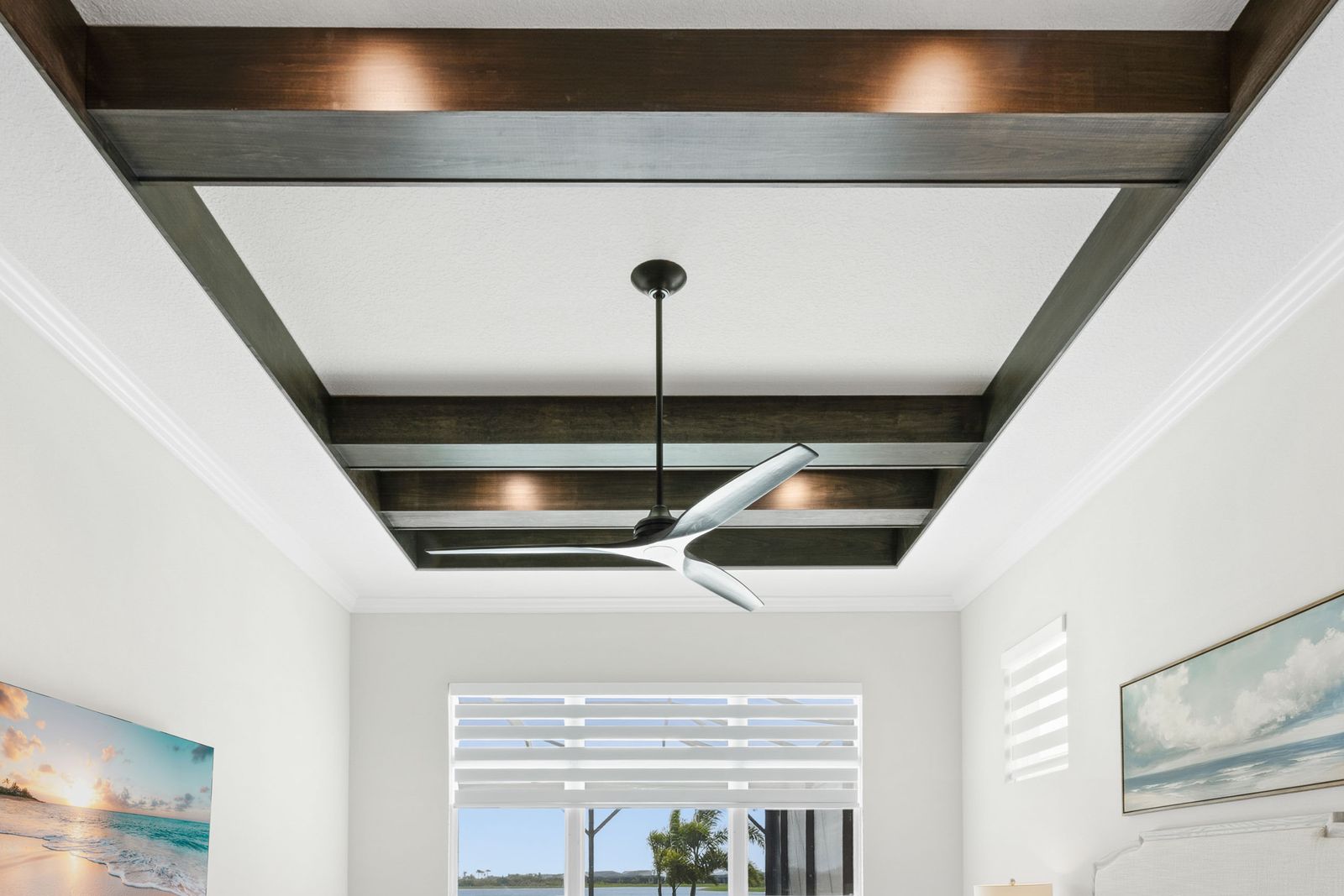 Primary bedroom with dark stained wood beams framing a white ceiling and a ceiling fan